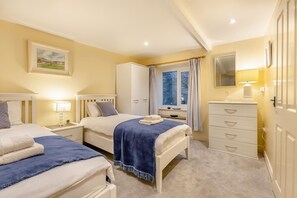 Ein Schlafzimmer mit zwei Betten, einem Kleiderschrank, einem Fenster mit Vorhängen und einer Nachttischlampe.