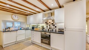 A kitchen with white cabinets, a built-in oven, a window, and a clock on the wall. - 3 Bed in Gunnerside (oc-t28301) (Satron)