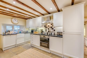 A kitchen with white cabinets, a built-in oven, a window, and a clock on the wall.