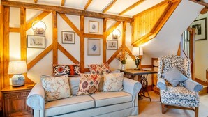 A cozy living room with a sofa and armchair, wooden beams, and framed artwork on the walls. - 3 Bed in Gressenhall (oc-s28418) (Gressenhall)