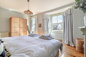 Une chambre avec un grand lit, une armoire en bois et une fenêtre avec des rideaux.