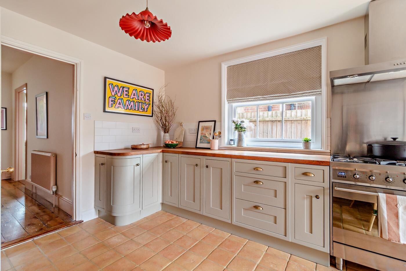 A kitchen with light-colored cabinets, a stainless steel stove, and a window with a view of a wooden deck.