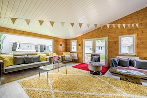 Ein gemütliches Blockhäuschen-Interieur mit Holzausstattung, einer Couch, einem Sessel, einem Couchtisch und einem roten Teppich.