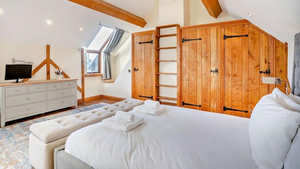 A bedroom with a bed, a dresser, a TV, and wooden wardrobes. - 4 Bed in Nottage (oc-t28401) (Nottage)