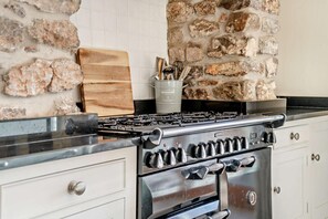 A kitchen with a gas stove, oven, and a stone wall backsplash. - 4 Bed in Nottage (oc-t28401) (Nottage)