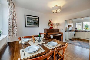 Un coin repas agrémenté d’un piano, d’un tableau encadré et d’une décoration sur le thème de la voile.