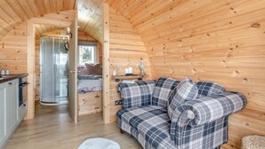 Ein gemütliches Blockhaus-Interieur mit Holzbalkendecke, einer Couch, einer Küchenzeile und einem kleinen Esstisch.