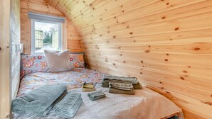 A cozy wooden room with a bed, pillows, and neatly folded towels. - 1 Bed in Crediton (oc-p28229) (Crediton Hamlets)