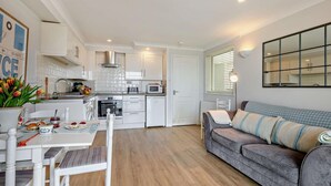 Een compacte woonruimte met een kitchenette, een eethoek en een bank.
