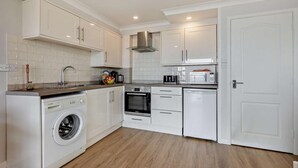 Een moderne keuken met witte kasten, een wasmachine, een oven en een magnetron.