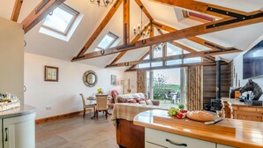 A spacious kitchen with a large island, wooden beams, skylights, and a view to the outdoors. - 2 Bed in Seahouses (oc-t19165) (Bamburgh)
