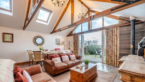 A cozy living room with a leather sofa, wooden coffee table, and a dining area with a wooden table and chairs. - 2 Bed in Seahouses (oc-t19165) (Bamburgh)