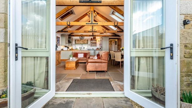 A spacious living area with a high ceiling, exposed wooden beams, and a cozy seating arrangement. - 2 Bed in Seahouses (oc-t19165) (Bamburgh)
