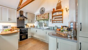 A kitchen with white cabinets, a wooden countertop, a stove, and a clock on the wall. - 2 Bed in Seahouses (oc-t19165) (Bamburgh)