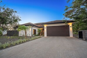 Ein modernes Haus mit gepflasterter Auffahrt, Garage und angelegtem Garten.