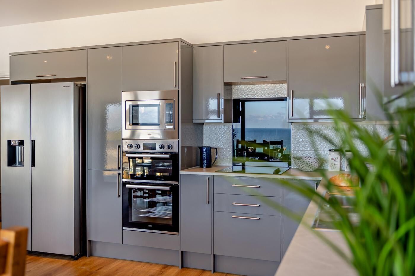 Une cuisine moderne dotée d’appareils électroménagers intégrés, de meubles de couleur grise et offrant une vue sur la mer.