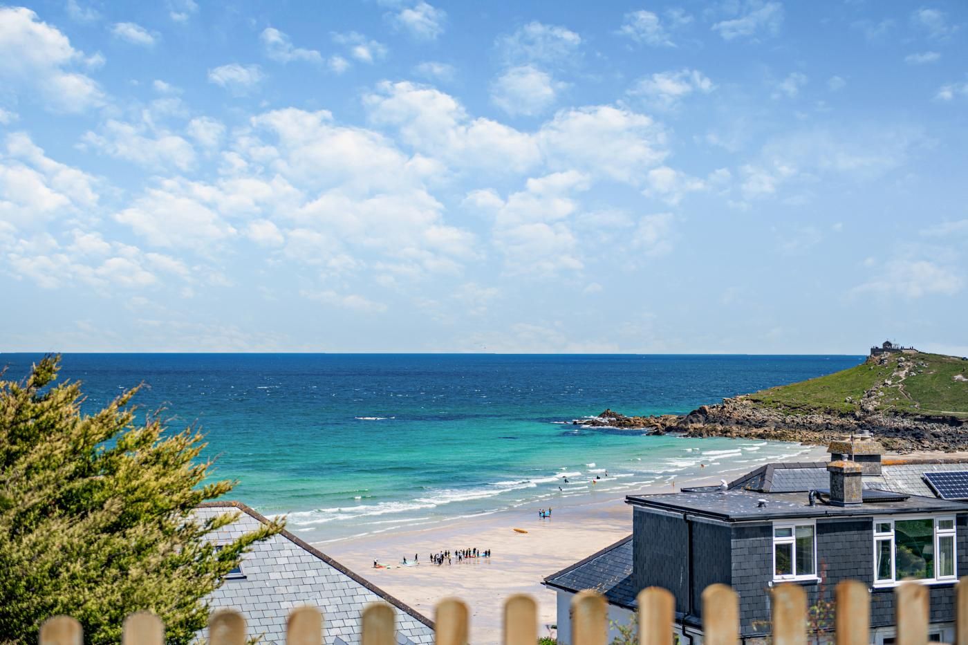A coastal view with a beach, ocean, and a hill with a structure on top.