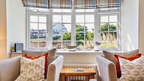 A cozy room with two armchairs, a small table with a plate of cookies and a cup, and a bay window with a view of the outside. - 4 Bed in Craster (oc-t28831) (Dunstan)