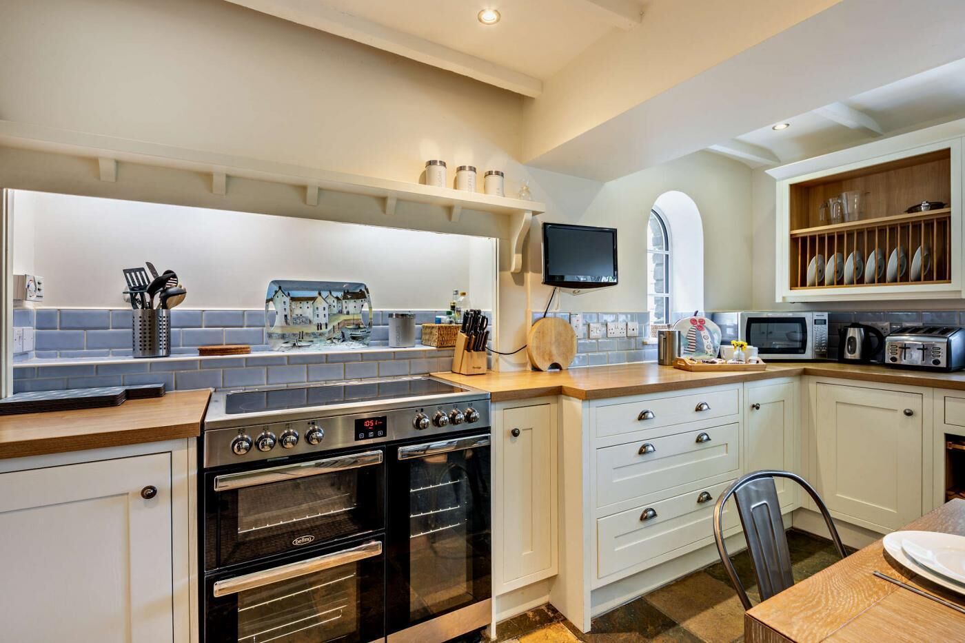 A modern kitchen with white cabinetry, a built-in oven, a microwave, and a coffee machine.