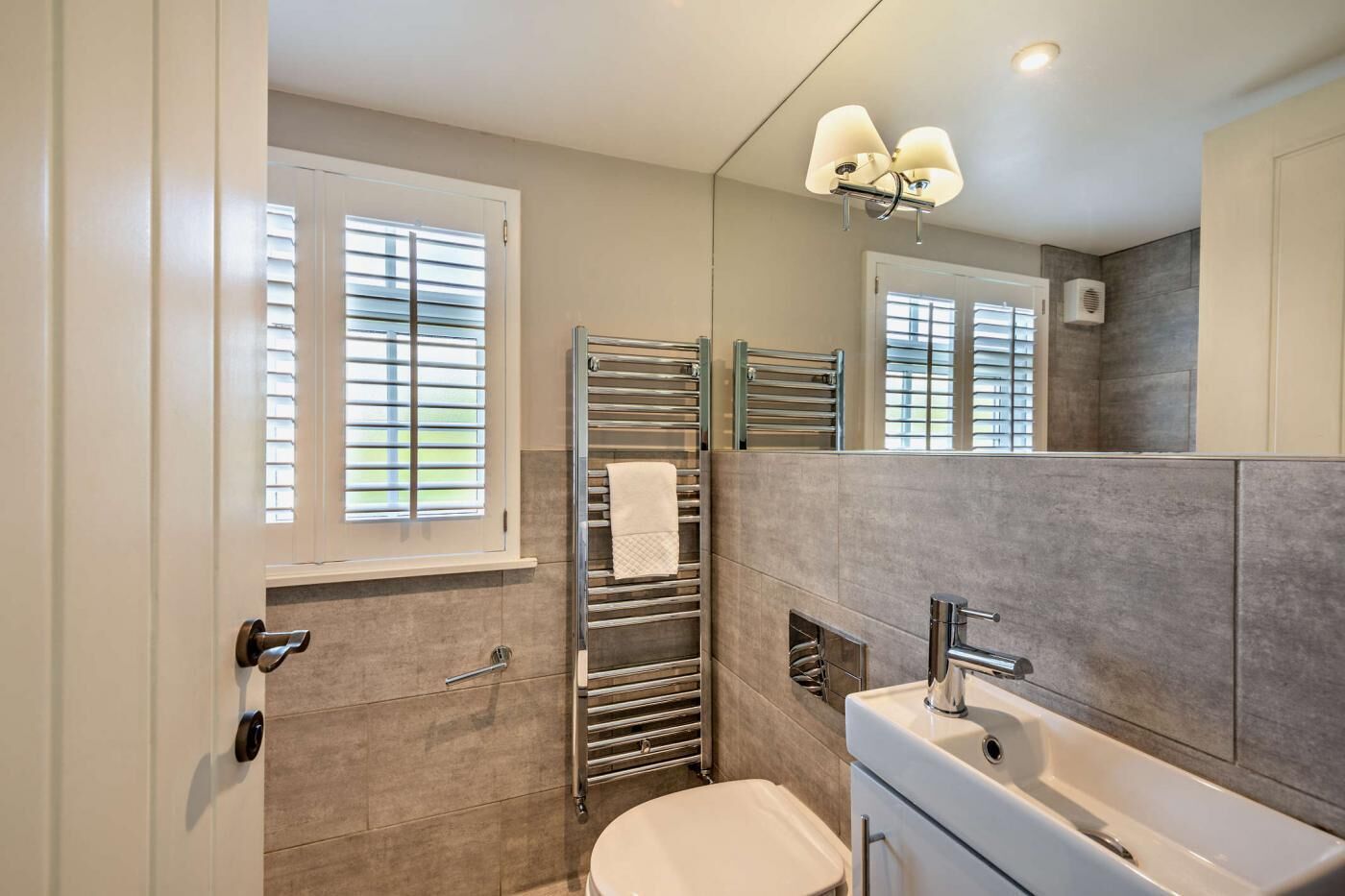 A modern bathroom with a toilet, sink, and towel racks.