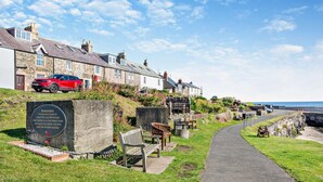 A coastal memorial site with a paved walkway, benches, and a plaque. - 4 Bed in Craster (oc-t28831) (Dunstan)
