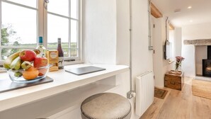 A modern kitchen with a large window, a fruit bowl, a bottle of wine, and a laptop on the counter. - 1 Bed in Cardinham (oc-s28796) (Cardinham)