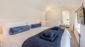 A bedroom with a large bed, a bedside table, a mirror, and a view of the bathroom. - 1 Bed in Cardinham (oc-s28796) (Cardinham)