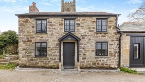 A stone building with a central entrance, multiple windows, and a chimney. - 1 Bed in Cardinham (oc-s28796) (Cardinham)