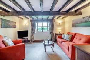 A living room with a TV, two sofas, a coffee table, and a window with curtains. - 2 Bed in Mutford (oc-p28440) (Mutford)
