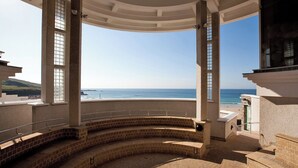 Ein überdachter Außenbereich mit einer gebogenen Ziegelbank, einer Brüstung und Blick auf das Meer.