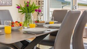 A breakfast table set with plates, glasses, and a vase of flowers. - 3 Bed in St. Merryn (oc-s28856) (Penrose)