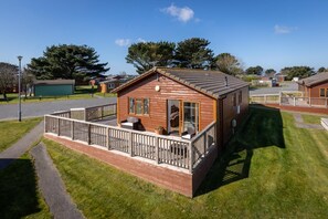 A wooden cabin with a balcony, a small porch, and a clear view of the surrounding area.