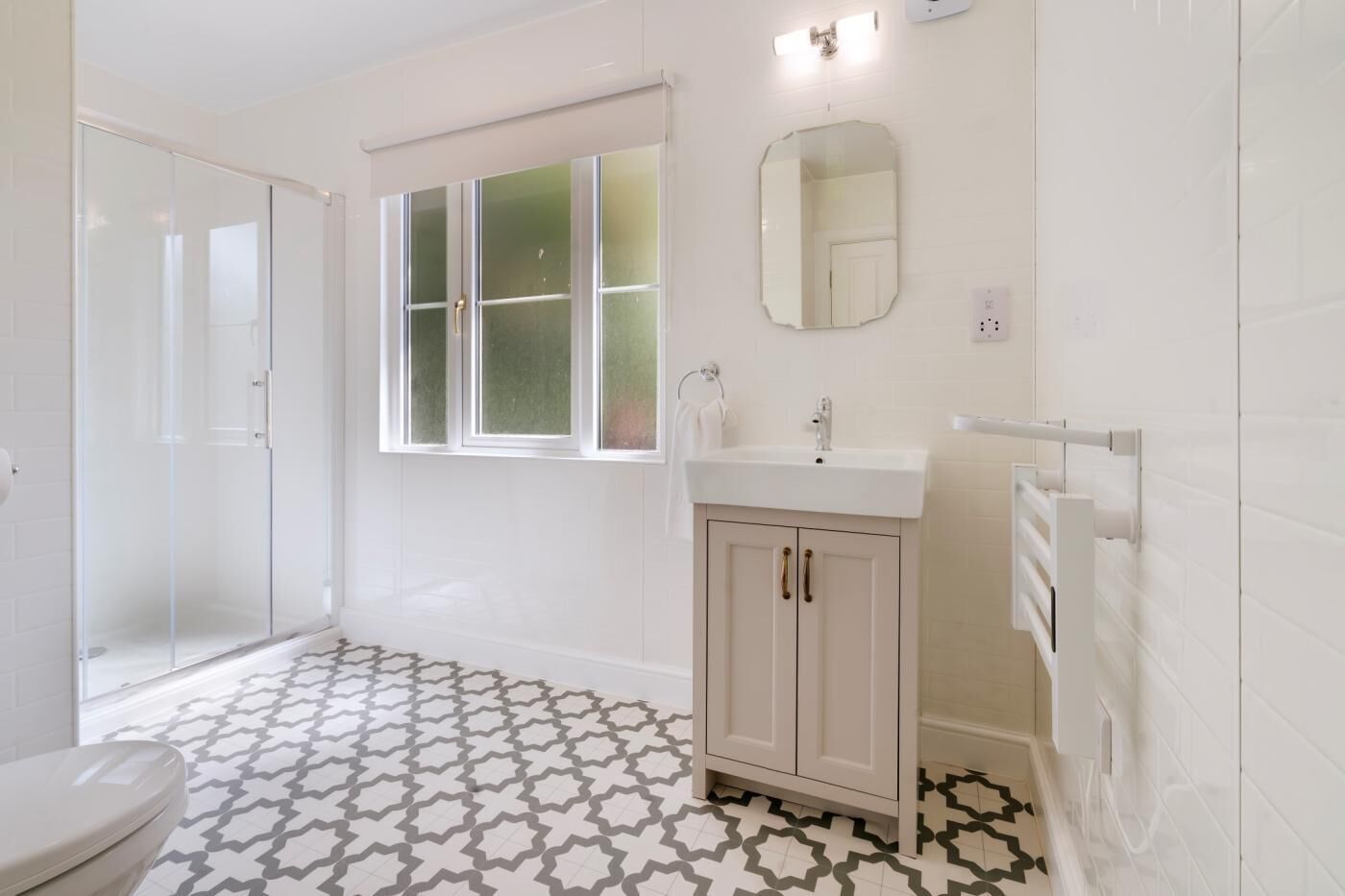Een badkamer met douche, toilet, wastafel en raam.