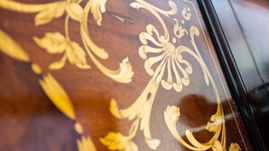 Detailaufnahme einer Holzoberfläche mit aufwendigen goldenen Mustern.
