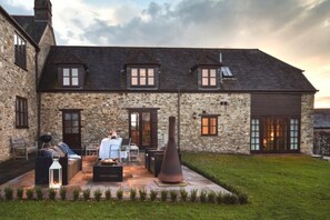 A stone building with a large patio area, outdoor seating, and a well-maintained lawn. - 3 Bed in Upottery (oc-t28827) (Upottery)