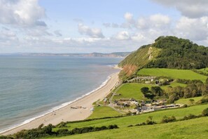 A coastal landscape with a beach, a small village, and a hill with dense vegetation. - 3 Bed in Upottery (oc-t28827) (Upottery)