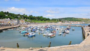 A harbor with numerous boats docked, a stone quay, and buildings in the background. - 3 Bed in Upottery (oc-t28827) (Upottery)
