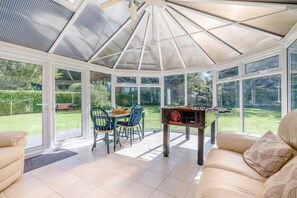 Ein Wintergarten mit einer Kicker-Tisch, einem Esstisch mit Stühlen und einer Couch.