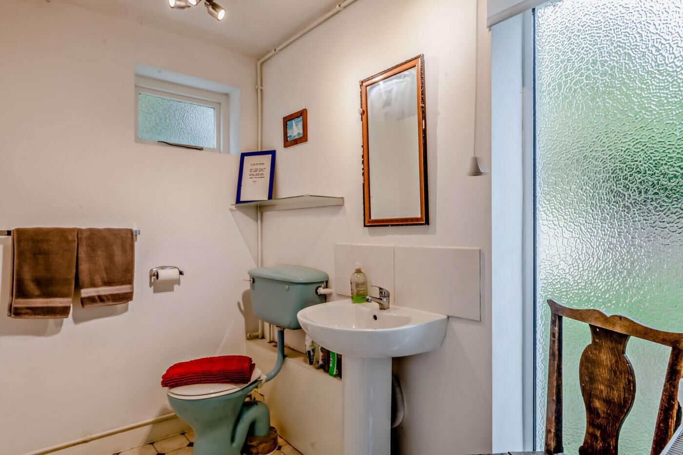 A bathroom with a toilet, sink, and towel rack.