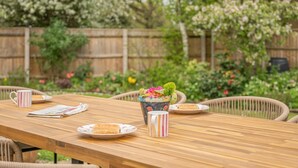 Une table de pique-nique en bois, avec des assiettes, des gobelets et un saladier décoratif.