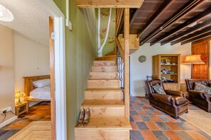 Un escalier en bois mène à une chambre à coucher qui contient un lit et une table de chevet.