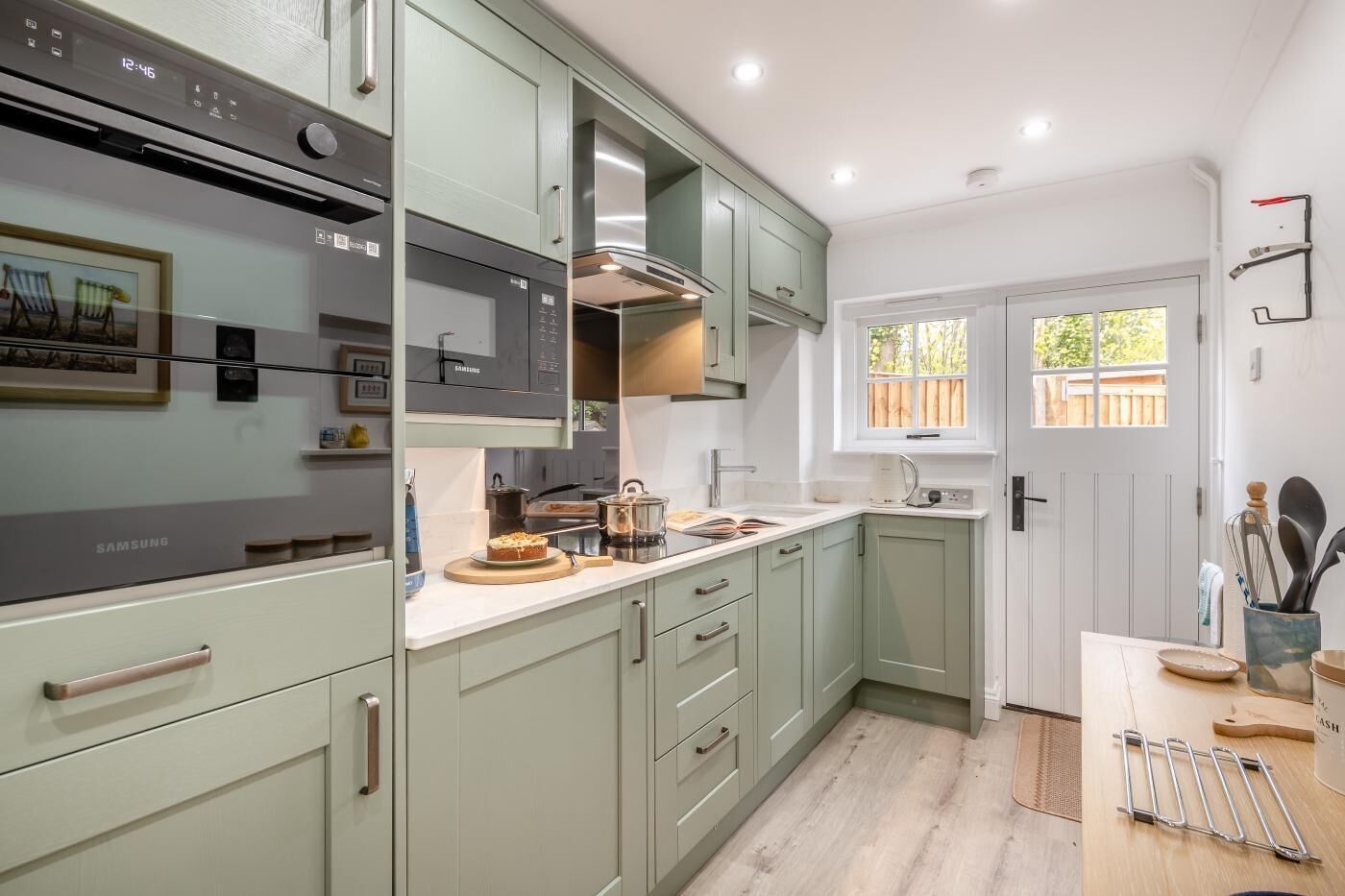 A modern kitchen with a built-in microwave, stainless steel oven, and a window providing natural light.
