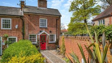 A brick house with a red door, a small garden, and a brick wall.
