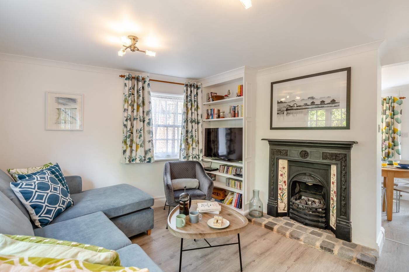 A living room with a grey sofa, a coffee table, a fireplace, and a bookshelf.