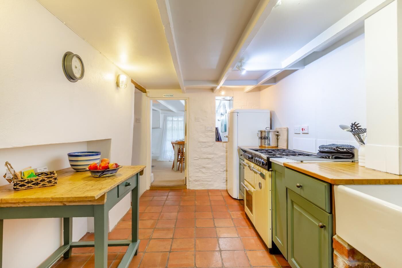 A compact kitchen with a wooden table, a stove, and a refrigerator.