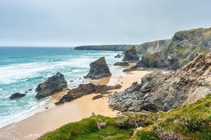 A coastal landscape with rocky cliffs, a sandy beach, and a clear view of the ocean. - 4 Bed in Retorrick Mill (oc-w28897) (Saint Mawgan)
