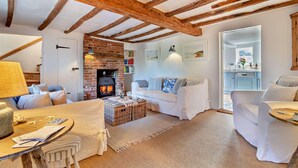 A cozy living room with a fireplace, white furniture, and exposed wooden beams. - 3 Bed in Dunwich (oc-l18684) (Dunwich)