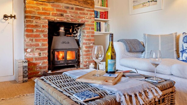 A cozy living room with a brick fireplace, a white sofa, and a bookshelf. - 3 Bed in Dunwich (oc-l18684) (Dunwich)