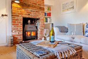 Un salon chaleureux avec une cheminée en briques, un canapé blanc et une bibliothèque.