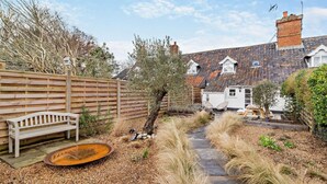 A garden with a wooden bench, a small pond, and a pathway leading to a white house with a tiled roof. - 3 Bed in Dunwich (oc-l18684) (Dunwich)